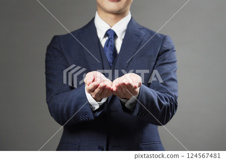 Businessman holding out both hands, black background, no face 124567481