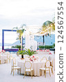 Laid festive table with a bouquet of flowers stands on a terrace with a glowing garland of light bulbs 124567554
