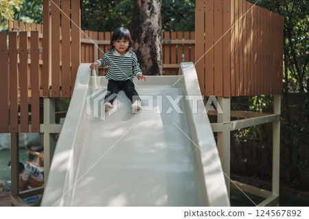 toddler baby girl sliding and playing at playground 124567892