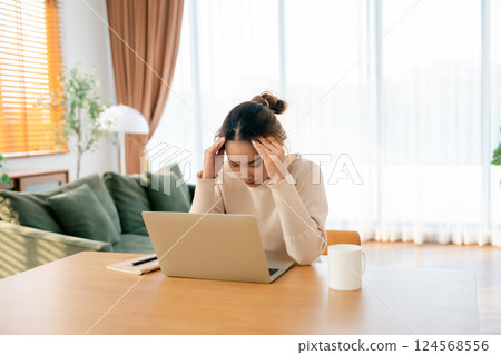 Thoughtful tired woman working on laptop computer looking on screen thinking solving problem at home 124568556