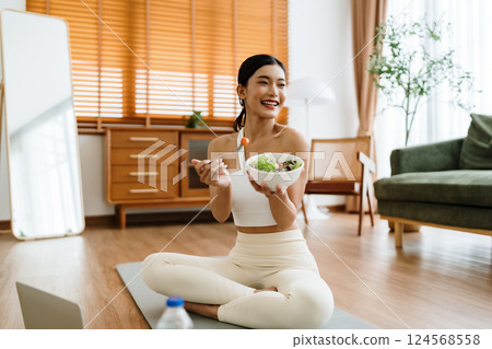 Healthy Asian Woman Enjoying Fresh Salad at Home After Yoga Workout 124568558
