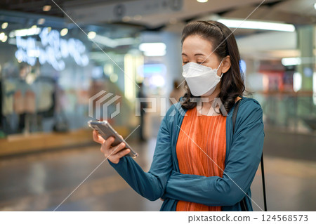 Asian Thai woman wears masks and plays mobile phone in a department or convenience store. Asian Thai woman wears masks and plays mobile phone in a department or convenience store. 124568573