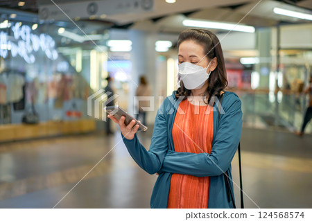 Asian Thai woman wears masks and plays mobile phone in a department or convenience store. Asian Thai woman wears masks and plays mobile phone in a department or convenience store. 124568574
