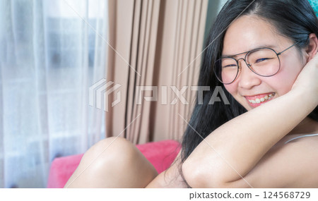 Asian Glasses Woman relax on her bed in the morning at her bedroom. 124568729