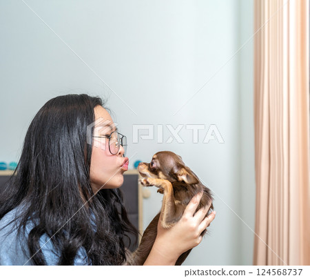 A lovely moment of a girl kiss her brown dog, Chi Hua Hua and it feels her love. A lovely moment of a girl kiss her brown dog, Chi Hua Hua and it feels her love. 124568737