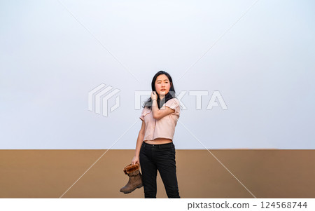 Asian woman holds brown boots in her hand and posting for photo shooting at rooftop environment at twilight time. Asian woman holds brown boots in her hand and posting for photo shooting at rooftop environment at twilight time. 124568744