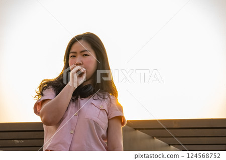 Asian glasses long hair girl is silhouette posting for camera shooting on the rooftop, top of building in twilight sunset time. Asian glasses long hair girl is silhouette posting for camera shooting on the rooftop, top of building in twilight sunset time. 124568752