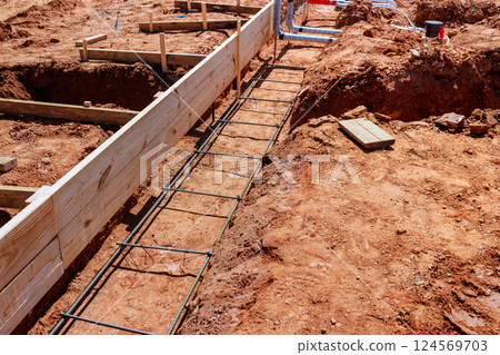 Workers prepare foundation with wooden forms, rebar, ensuring stability for upcoming construction. Workers prepare foundation with wooden forms, rebar, ensuring stability for upcoming construction. 124569703
