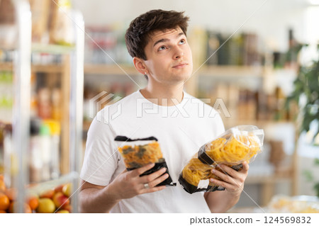 Interested young customer selecting pasta for dinner in supermarket 124569832