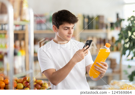 Guy scanning QR code on soft drink bottle in supermarket Guy scanning QR code on soft drink bottle in supermarket 124569864