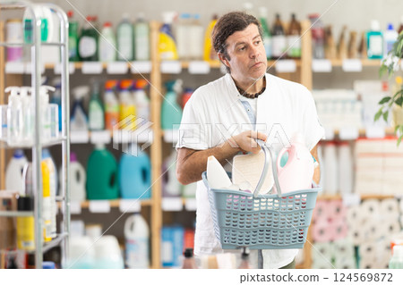 Adult man chooses household chemicals in store Adult man chooses household chemicals in store 124569872