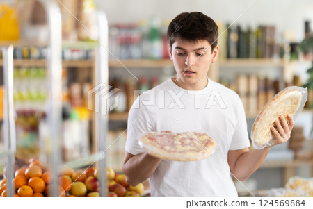 European guy looks at product and shop around, choose and buy pizza with different filling in shop 124569884