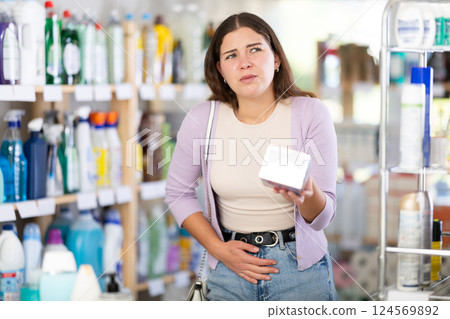 Woman with stomach pain chooses cosmetics Woman with stomach pain chooses cosmetics 124569892