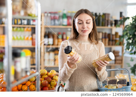 Young woman choosing pickled asparagus during shopping in grocery store 124569964