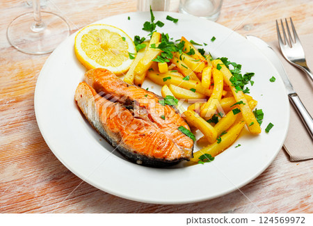 Salmon steak with vegetables side dish of fries 124569972