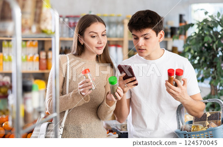 Couple man and woman scanning qr code for spices and seasonings Couple man and woman scanning qr code for spices and seasonings 124570045