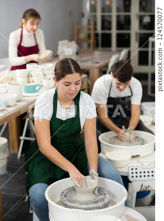 Young woman sculpting product on potter's wheel Young woman sculpting product on potter's wheel 124570077
