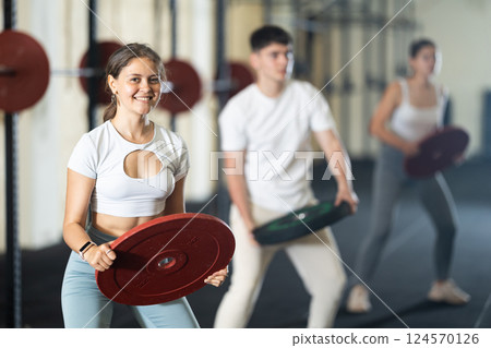 Young woman training with weight plate 124570126