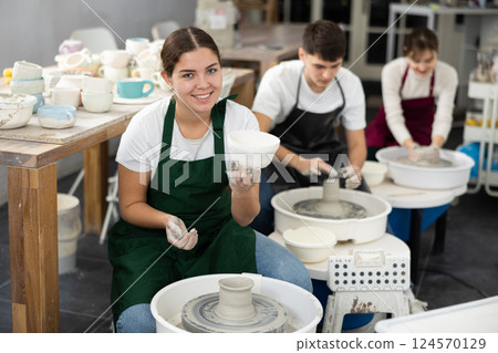 Young woman holding clay bawl at pottery wheel 124570129