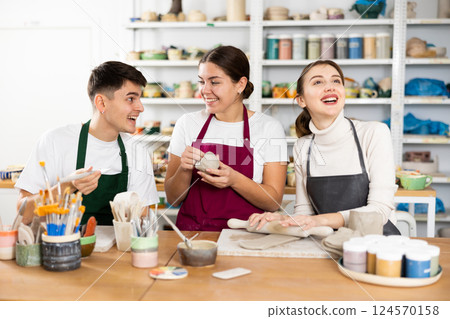 Two young women and young man making pottery 124570158