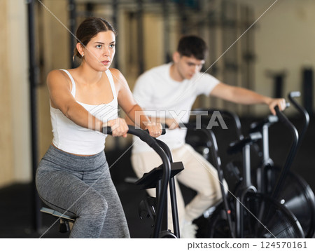 Young woman exercising on exercise bike in gym Young woman exercising on exercise bike in gym 124570161