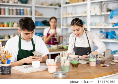 Young woman and young man making pottery 124570168