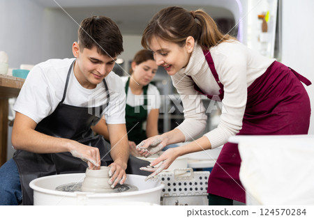 Young woman and young man sculpting product on potter's wheel Young woman and young man sculpting product on potter's wheel 124570284