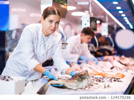 Portrait of saleswoman offering fresh fish atlantic cod at shop 124570286