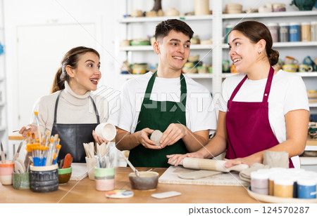 Joyous young man and women sculpting handmade cups 124570287