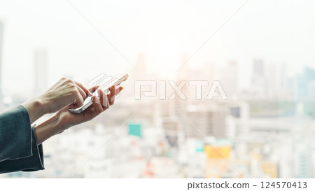 A woman who uses a smartphone against the backdrop of the city A woman who uses a smartphone against the backdrop of the city 124570413
