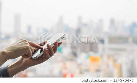 A woman who uses a smartphone against the backdrop of the city A woman who uses a smartphone against the backdrop of the city 124570475