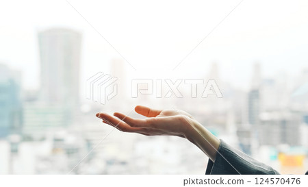 Woman holding her hands up against a city background Woman holding her hands up against a city background 124570476