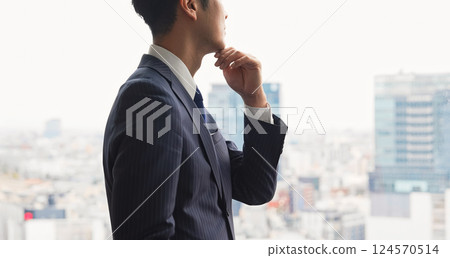 Businessman thinking while looking at the city from his office window 124570514