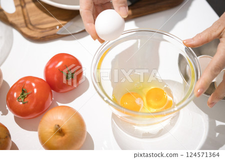中年婦女的手拿著碗裡剛打好的蛋 中年婦女的手拿著碗裡剛打好的蛋 124571364