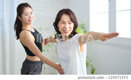 Middle-aged woman receiving lessons from a yoga instructor Middle-aged woman receiving lessons from a yoga instructor 124571373