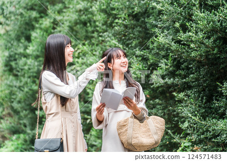 年輕的亞洲女性一邊看旅遊指南一邊在旅遊景點周圍散步(女孩的旅行、旅行、旅遊) 年輕的亞洲女性一邊看旅遊指南一邊在旅遊景點周圍散步(女孩的旅行、旅行、旅遊) 124571483