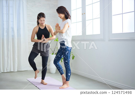 Middle-aged woman receiving lessons from a yoga instructor 124571498