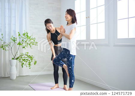 Middle-aged woman receiving lessons from a yoga instructor Middle-aged woman receiving lessons from a yoga instructor 124571729