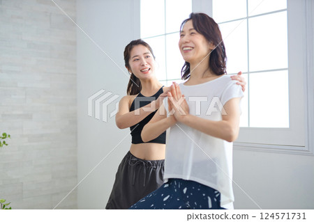 Middle-aged woman receiving lessons from a yoga instructor Middle-aged woman receiving lessons from a yoga instructor 124571731