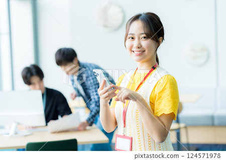 A young woman operating a smartphone in the office A young woman operating a smartphone in the office 124571978