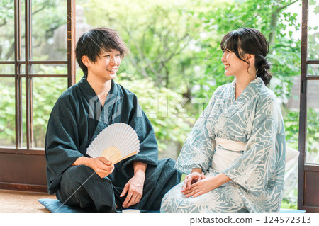 穿著浴衣的亞洲夫婦坐在日本房子的門廊上 穿著浴衣的亞洲夫婦坐在日本房子的門廊上 124572313