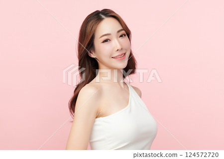 A beautiful young Asian woman with clean, fresh skin against a pink background. Skincare, facial treatment, cosmetology, beauty, and spa. An elegant portrait of an Asian woman. 124572720