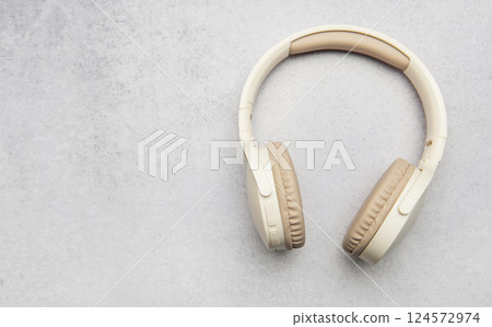 Modern wireless headphones lying on gray stone background 124572974