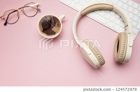 Coffee break accessories on pink table, headphones, keyboard and glasses Coffee break accessories on pink table, headphones, keyboard and glasses 124572979