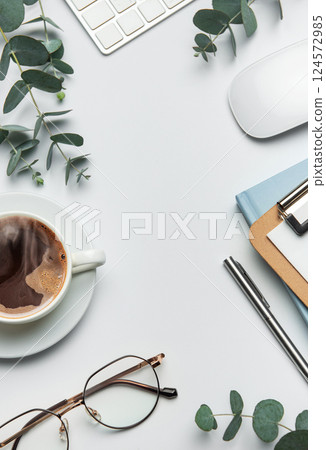 Eucalyptus branches, coffee, keyboard, and mouse framing white desk background 124572985