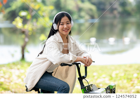 A woman looking happily at her notebook as she figure something out while sitting on park sidewalk 124574052