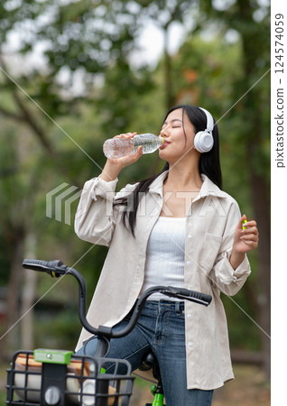 A woman looking happily at her notebook as she figure something out while sitting on park sidewalk 124574059