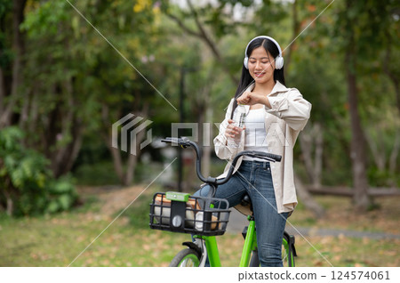 A woman looking happily at her notebook as she figure something out while sitting on park sidewalk 124574061