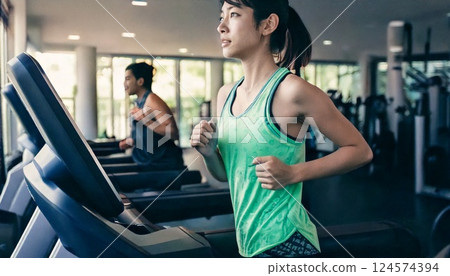 Woman running on a running machine in a gym 124574394