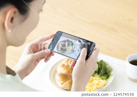Diet: A woman taking pictures of food with her smartphone Diet: A woman taking pictures of food with her smartphone 124574539
